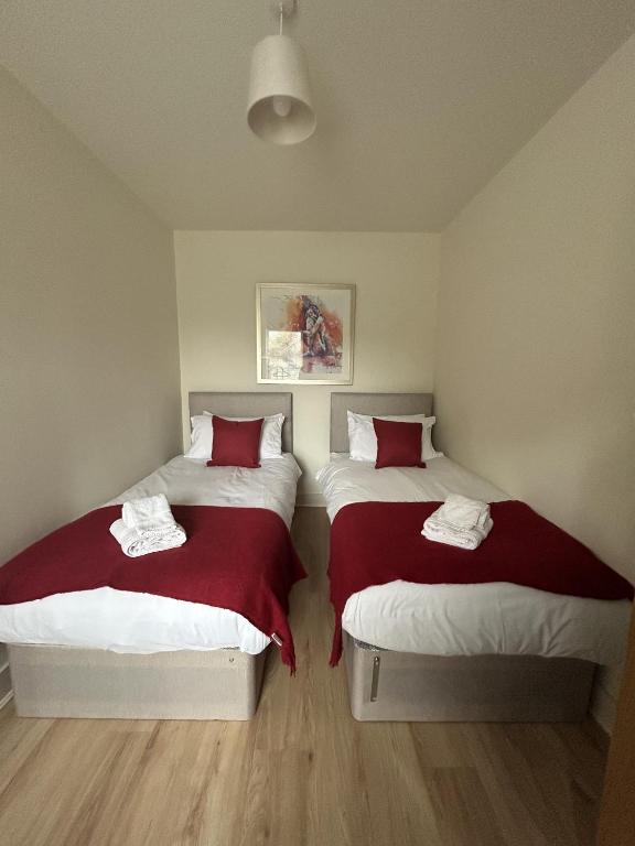 雷丁New 2 Bedroom Apartment in Reading的一间卧室配有两张红色和白色床单