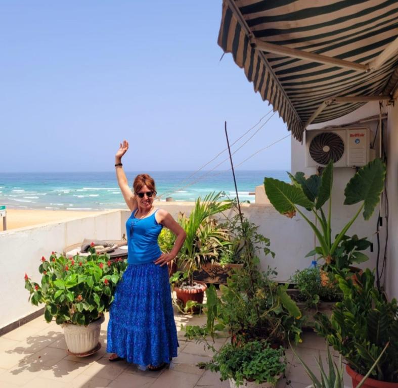 达喀尔Casa Djoko的站在海滩前身穿蓝色衣服的女人