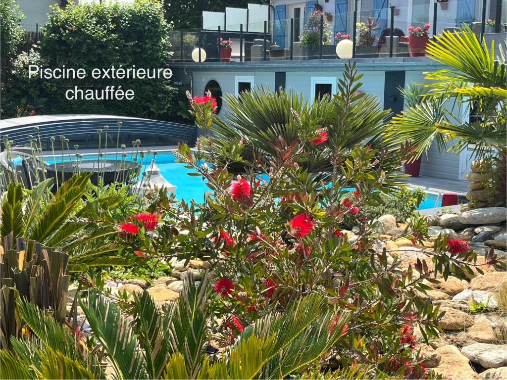 滨海维莱Hotel la piscine的一座种有红色鲜花的花园和一个游泳池