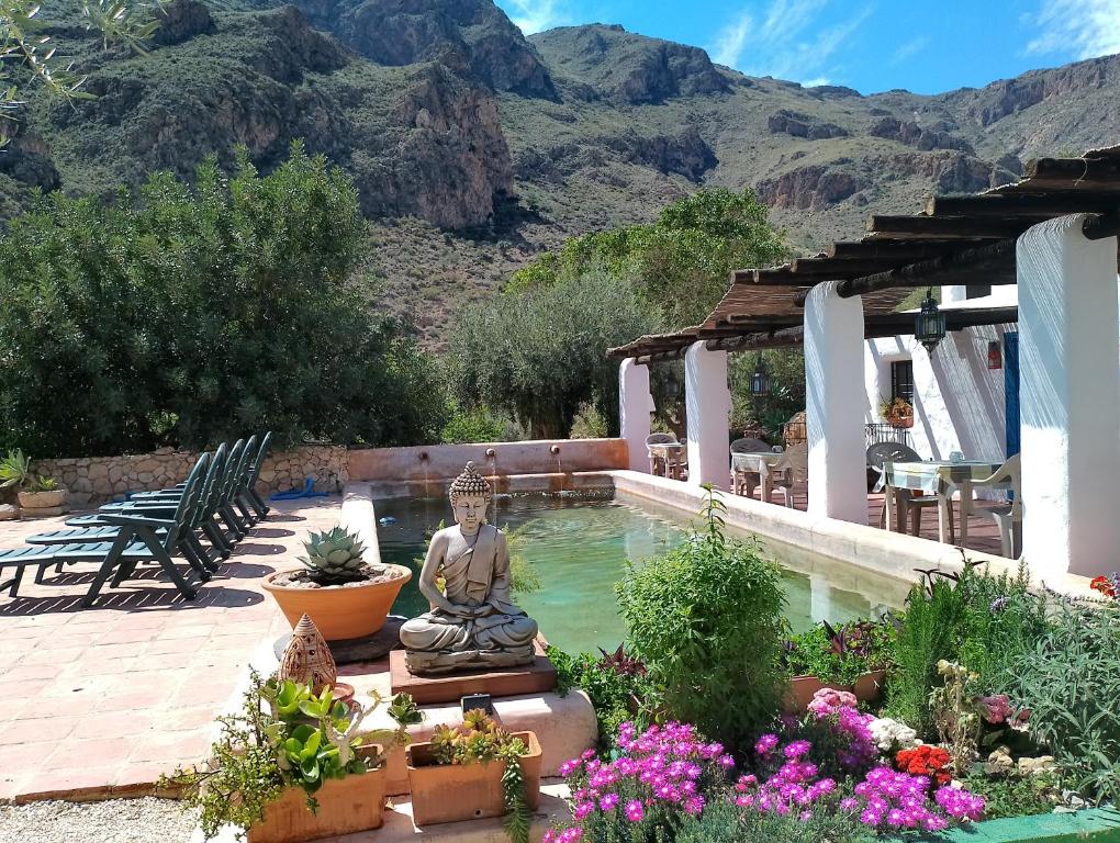 尼哈尔Hotel Rural Cortijo La Alberca的花园中一座带雕像的游泳池