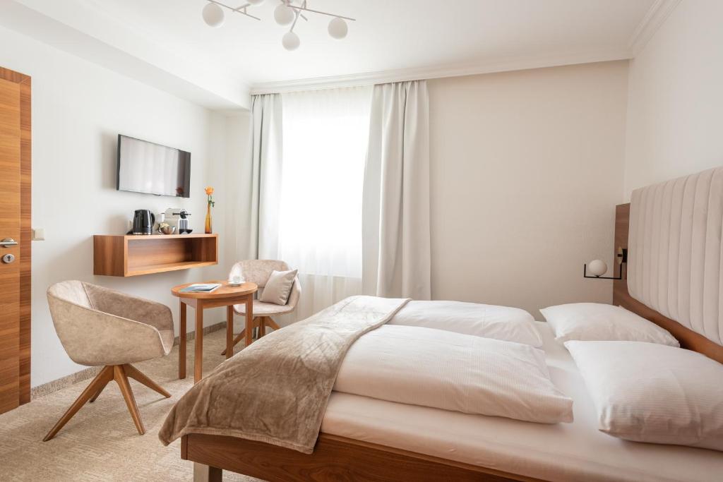 滨湖采尔das zellersee的卧室配有1张床、1张桌子和1把椅子