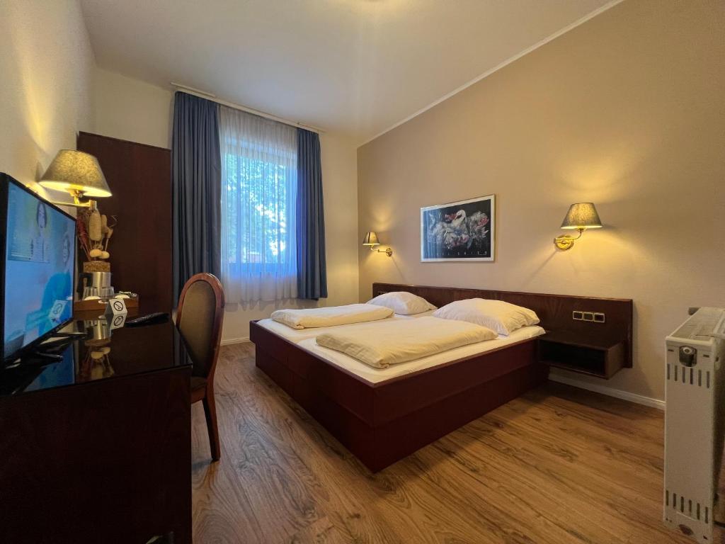 沃尔姆斯中心酒店的一间卧室配有一张床和一台平面电视