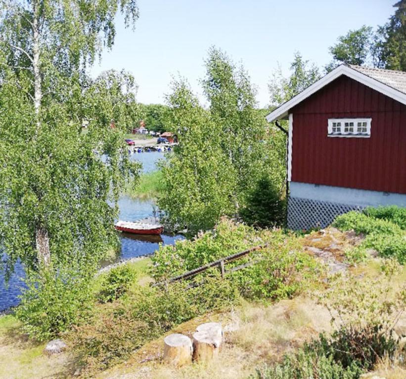 尼雪平House with lake plot and own jetty on Skansholmen outside Nykoping的一座红色的建筑和一条河,里面装着一条船