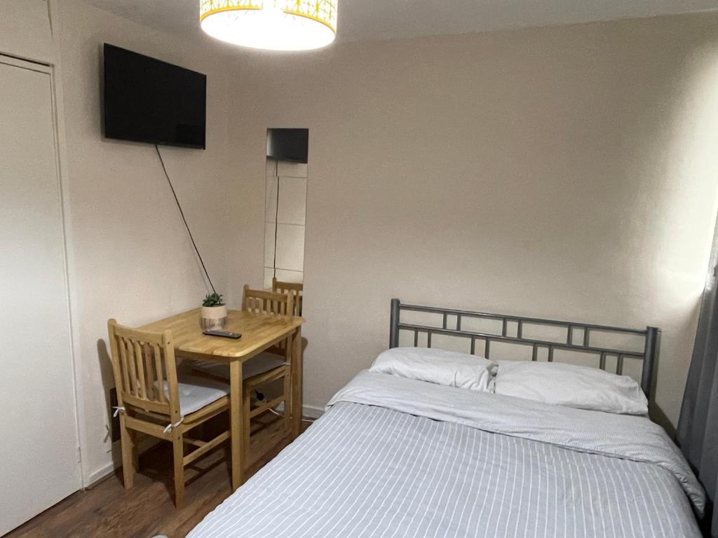 伦敦Comfortable double room的一间卧室配有一张床和一张桌子及一台电视