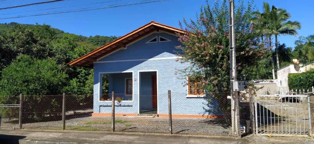波梅罗迪Casa Centenária no centro de Pomerode的 ⁇ 后面的蓝色小房子