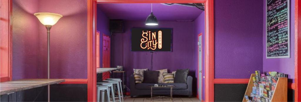 拉斯维加斯Sin City Hostel的紫色的客房配有一张沙发和一张桌子