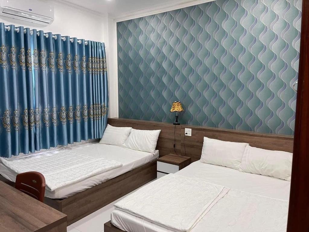 朱笃Kim Ngân Motel的一间卧室设有两张床和蓝色的墙壁