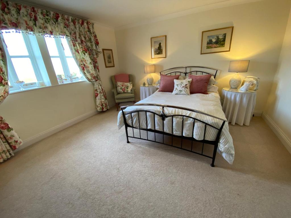 比明斯特Lower Farm Cottage的一间卧室设有床、两张桌子和一扇窗户