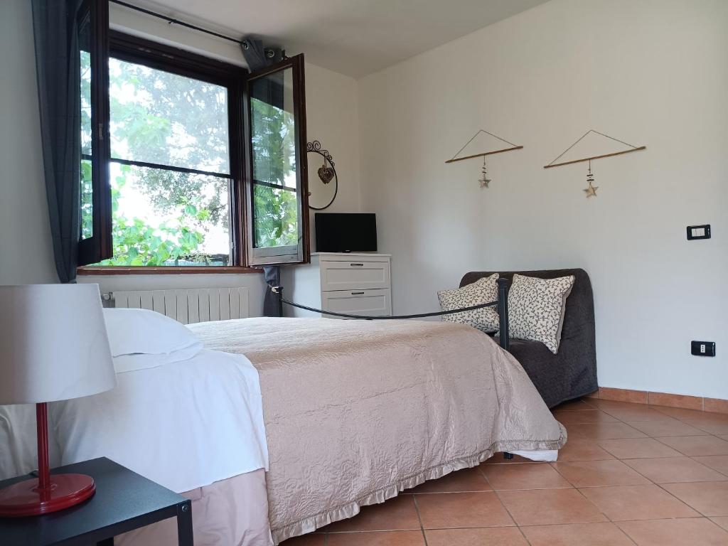 奥贝里塞Agriturismo Le Villette di Cate的一间卧室设有一张床、一台电视和一个窗口。
