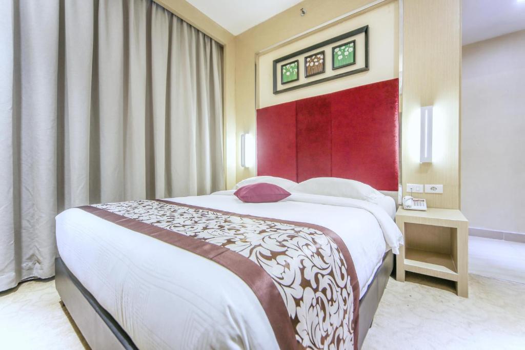 名古屋巴淡岛城市酒店的一间卧室设有一张大床和红色的墙壁