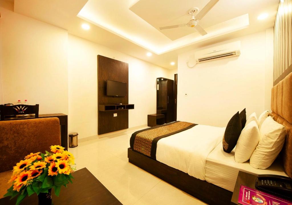 新德里Balwood Suites Near Delhi Airport的配有床和鲜花桌的酒店客房