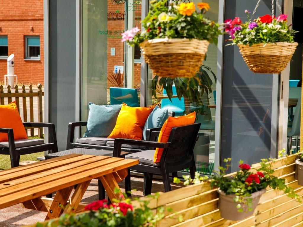 谢菲尔德谢菲尔德体育场宜必思快捷酒店的庭院配有椅子、桌子和鲜花