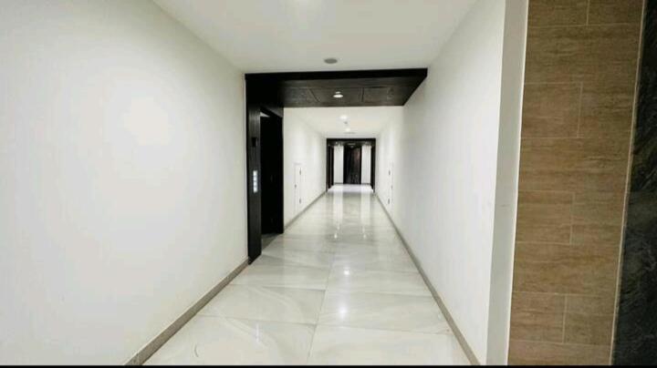 拉合尔Premium 1BR DHA Phase 5的一条空的走廊,有白色的墙壁,走廊上设有黑色的门