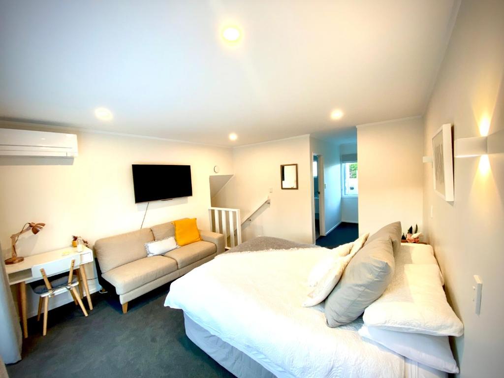 陶波2 Mile Bay Guesthouse的一间卧室配有一张床、一张沙发和一台电视。