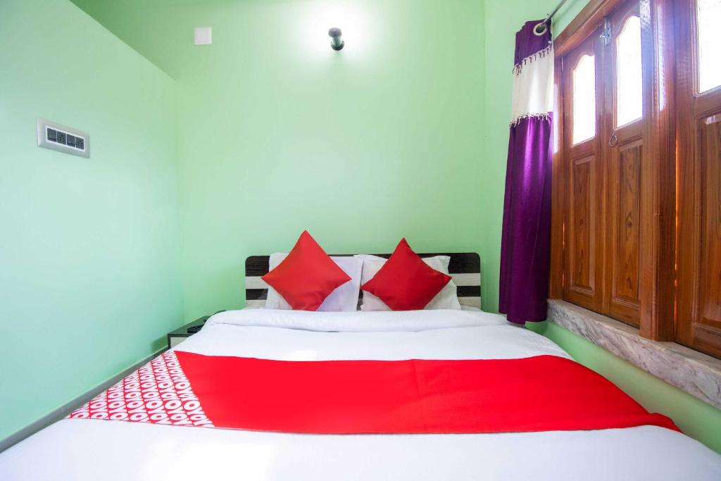 BaharampurOYO Hotel Taj International的一间卧室配有红色枕头的床