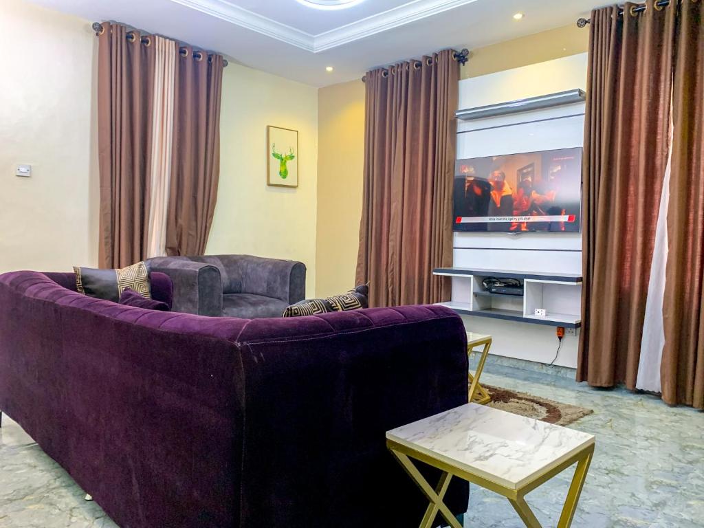 拉各斯28B (3/2B)的客厅配有紫色沙发和电视