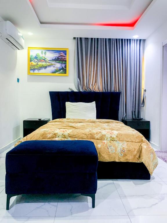 拉各斯60B Adetoun Adelaja 4Bedroom的一间卧室配有一张大床和蓝色的搁脚凳