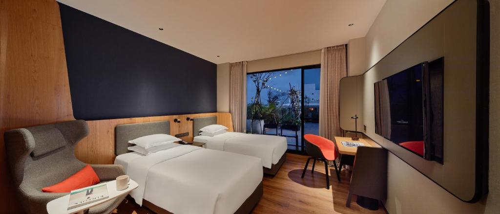 嘉义市嘉义智选假日酒店的一间卧室配有两张床、一张桌子和一台电视。