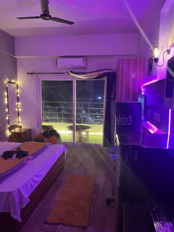 大诺伊达Bella Dreamy near expo mart greater Noida的一间卧室配有一张床和一个带紫色灯的窗户
