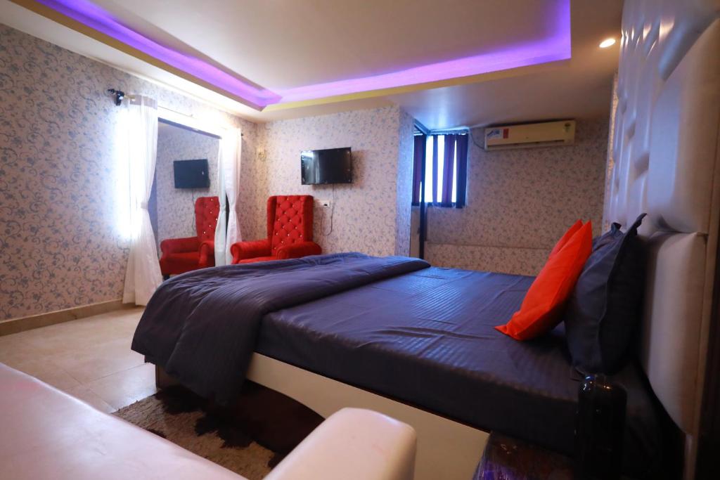 巴特那Raj Resort的一间卧室配有一张床和两张红色椅子