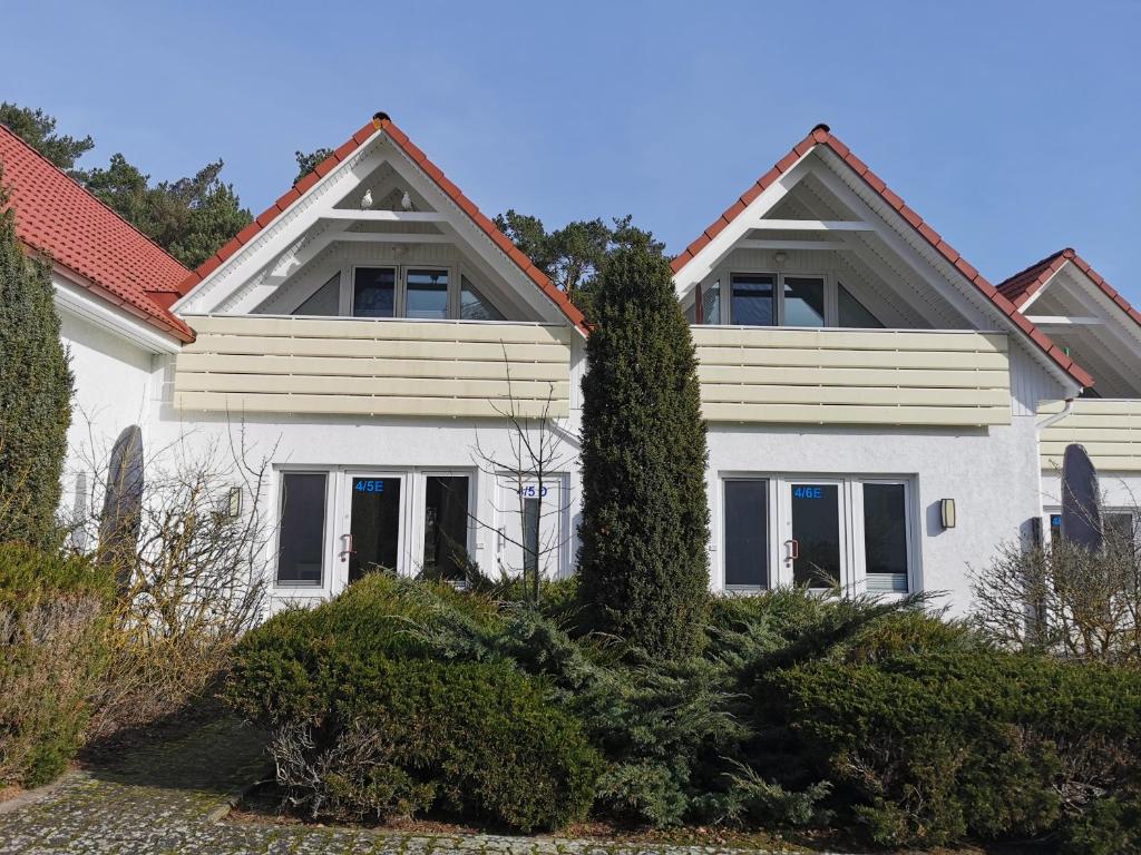 普雷罗Ferienanlage "Haus hinter den Dünen" Prerow的白色房子,有红色屋顶