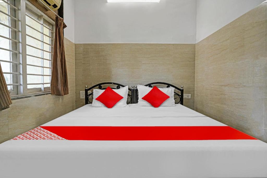 孟买OYO Flagship Raj Hotel Near Juhu Beach的一间卧室配有一张带红色枕头的大床