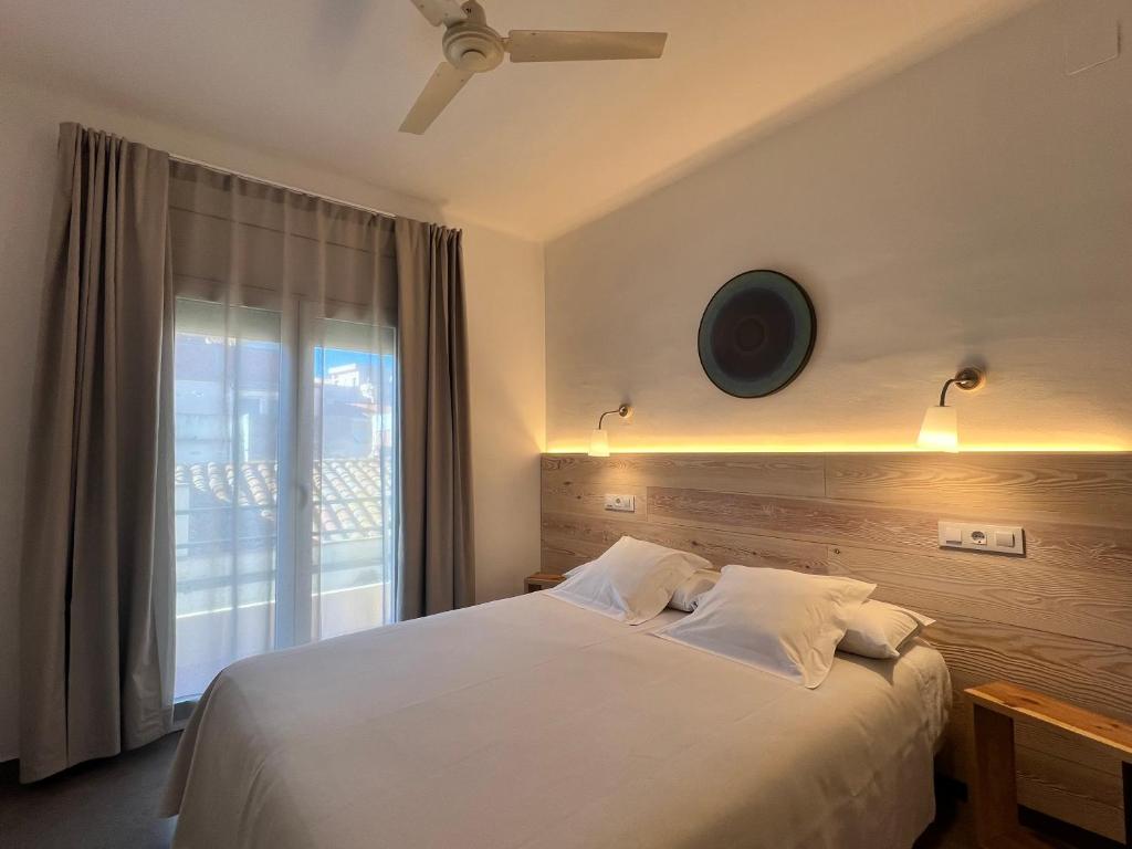 罗萨斯Hostal ROM Familiar的卧室配有白色的床和窗户。