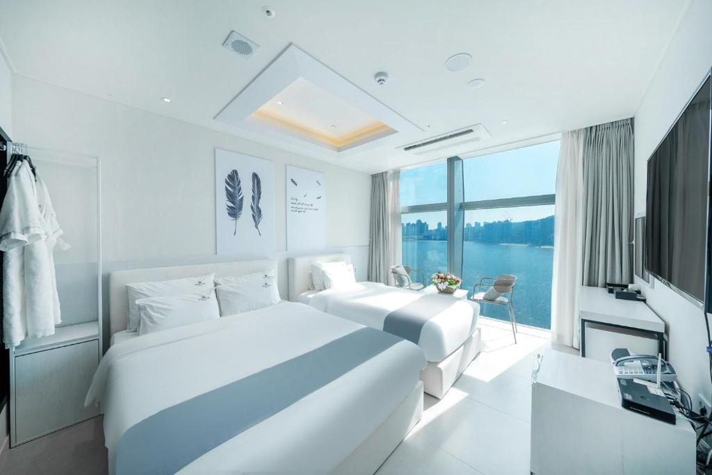 釜山Oceanstay Hotel的白色客房的两张床,设有大窗户