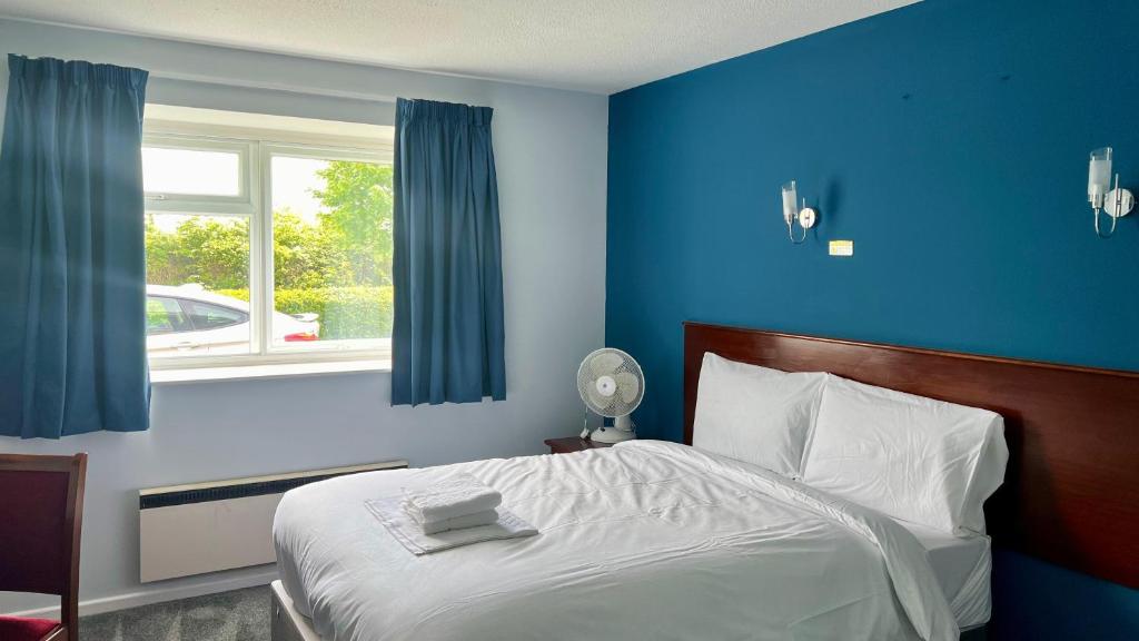 米尔顿凯恩斯MK Hotel的一间卧室配有一张蓝色墙壁的床和一扇窗户