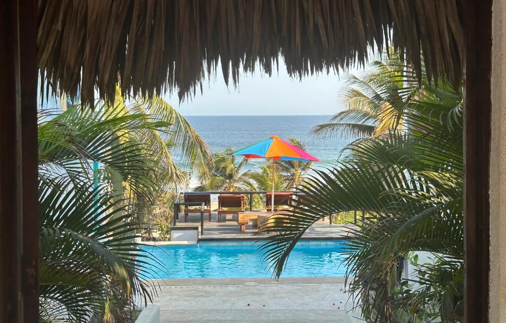 Santa María TonamecaBeachfront Paradise Boutique Hotel的享有带遮阳伞的游泳池和大海的景致。