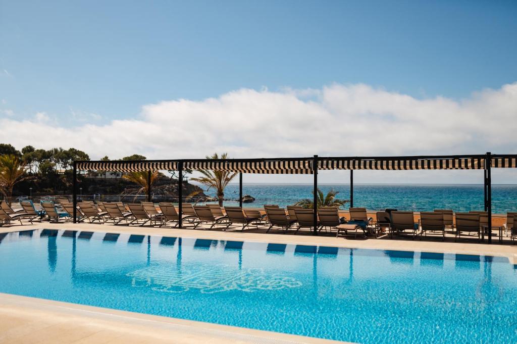 帕格拉Secrets Mallorca Villamil Resort & Spa - Adults Only (+18)的一个带椅子的游泳池,背景是大海