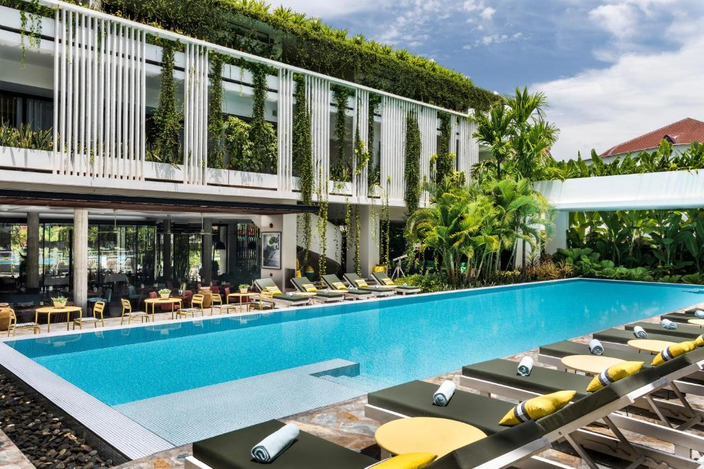 暹粒维鲁斯酒店的一座带躺椅的室外游泳池和一座建筑