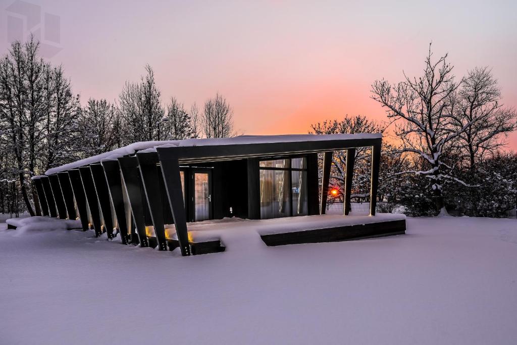 奥泰佩Tondikaku Holiday Home的雪中的小建筑,背景是日落