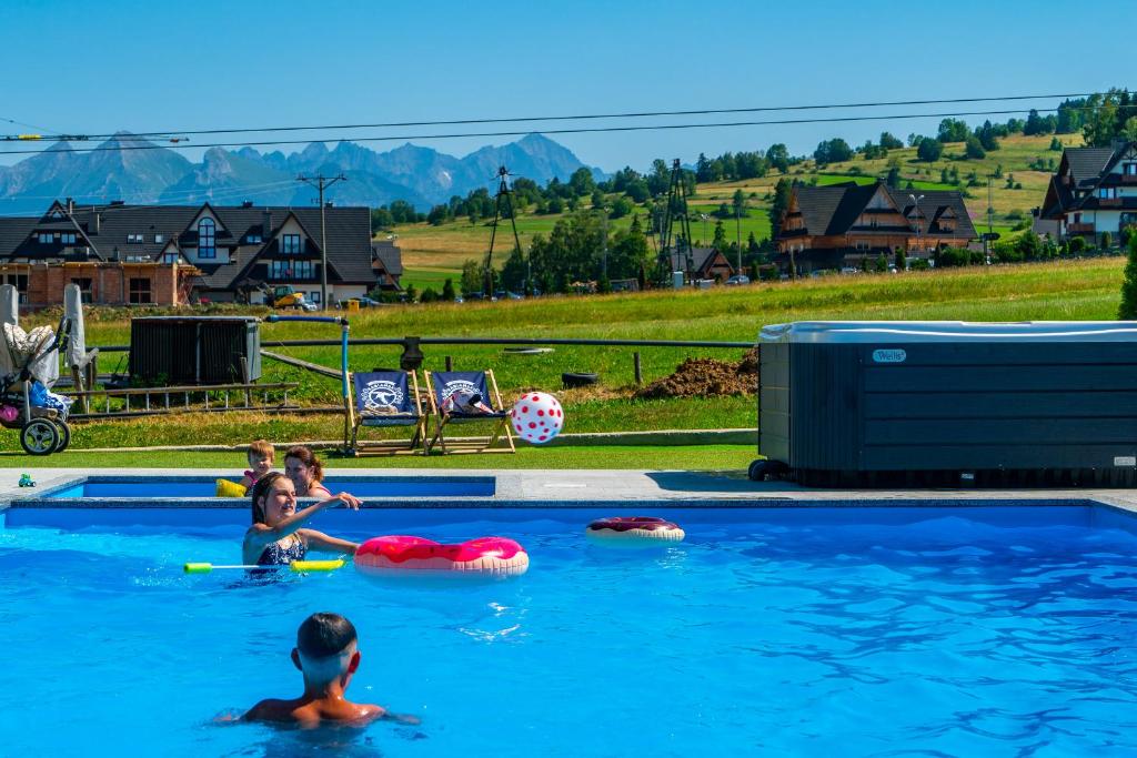 Białka TatrzanskaAparthotel Rabiań-SKI zewnętrzny basen oraz jacuzzi z podgrzewana wodą dmuchaniec i 2 place zabaw w cenie的一群儿童在游泳池玩耍