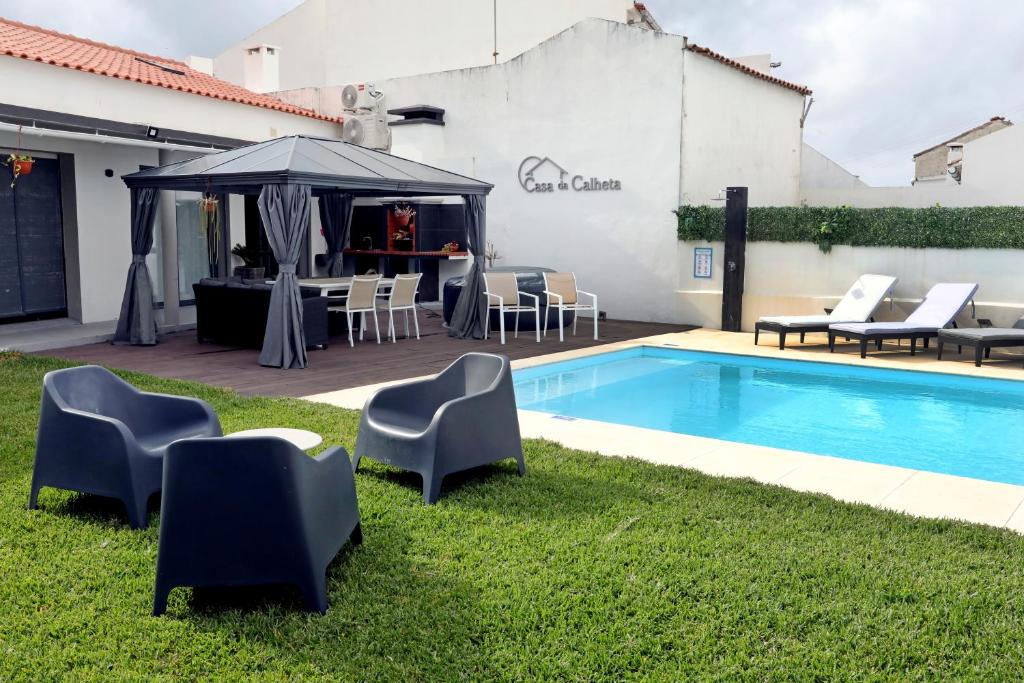 MaiaCasa da Calheta的一个带椅子和桌子的游泳池以及一把遮阳伞