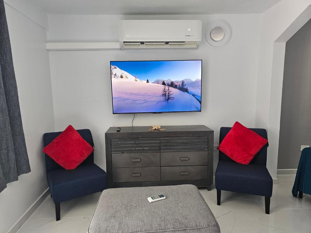 马亚圭斯Nala's Studio的客厅配有两把椅子和墙上的电视