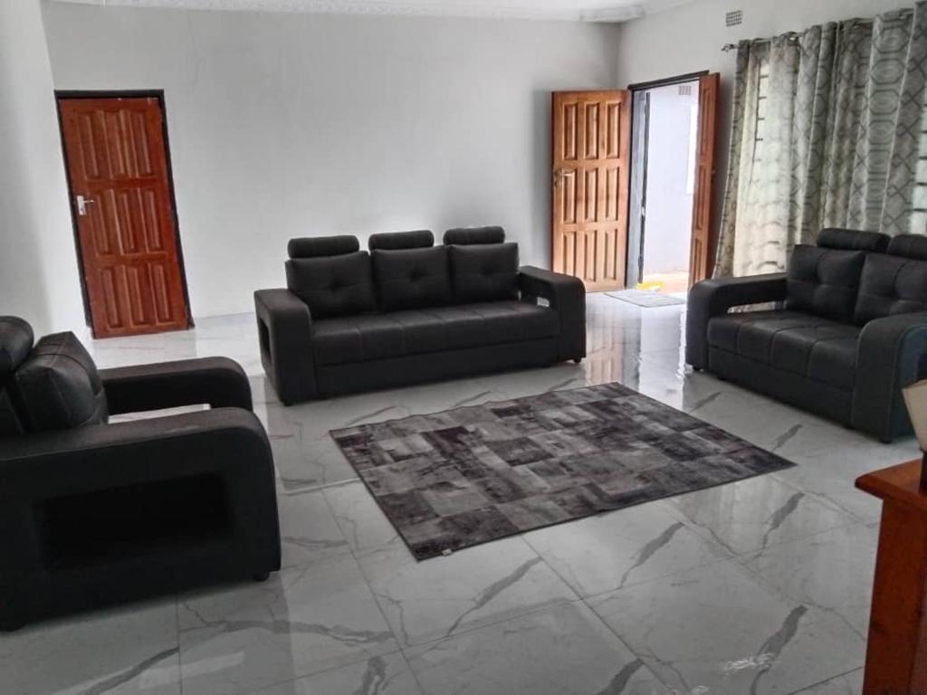 卢萨卡Radiant lodge的客厅配有两张黑色沙发和地毯。