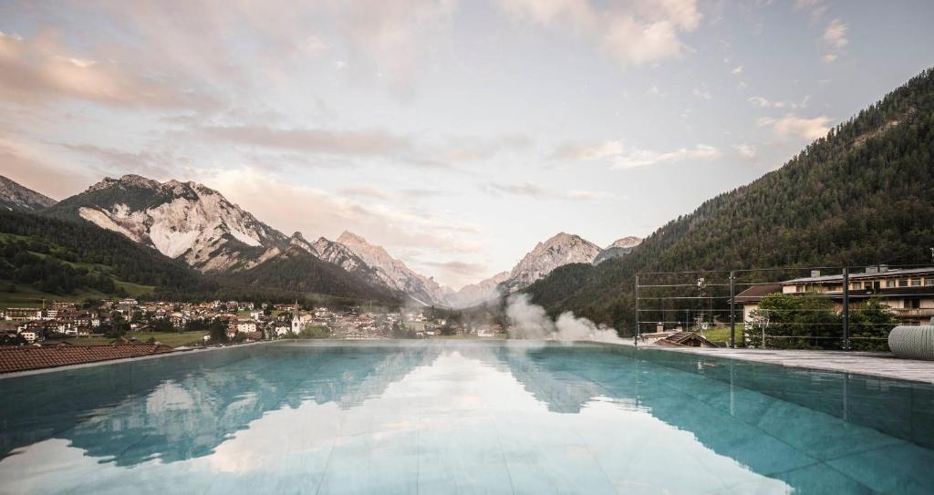 圣维吉利奥Excelsior Dolomites Life Resort的山水池的背景