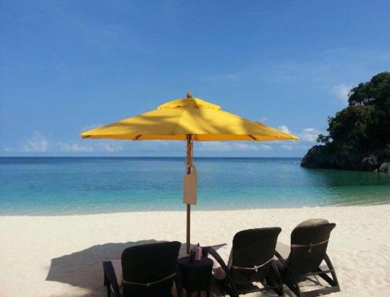 长滩岛Happy Diniwid Apartments的海滩上一把遮阳伞下的两把椅子