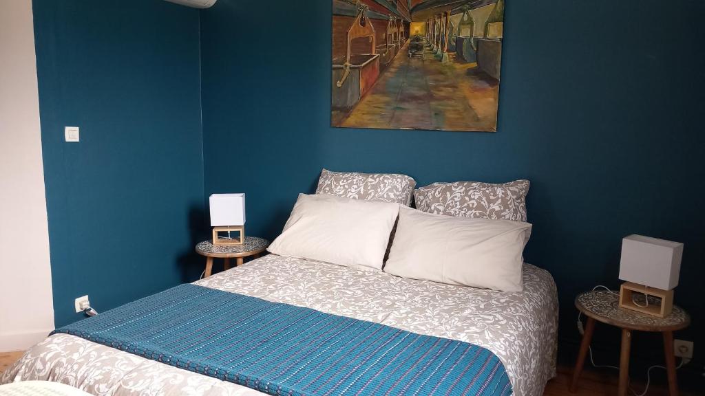 Saint-MathurinChambres d'hôtes bord de Loire的一间卧室拥有蓝色的墙壁,配有一张带白色枕头的床。