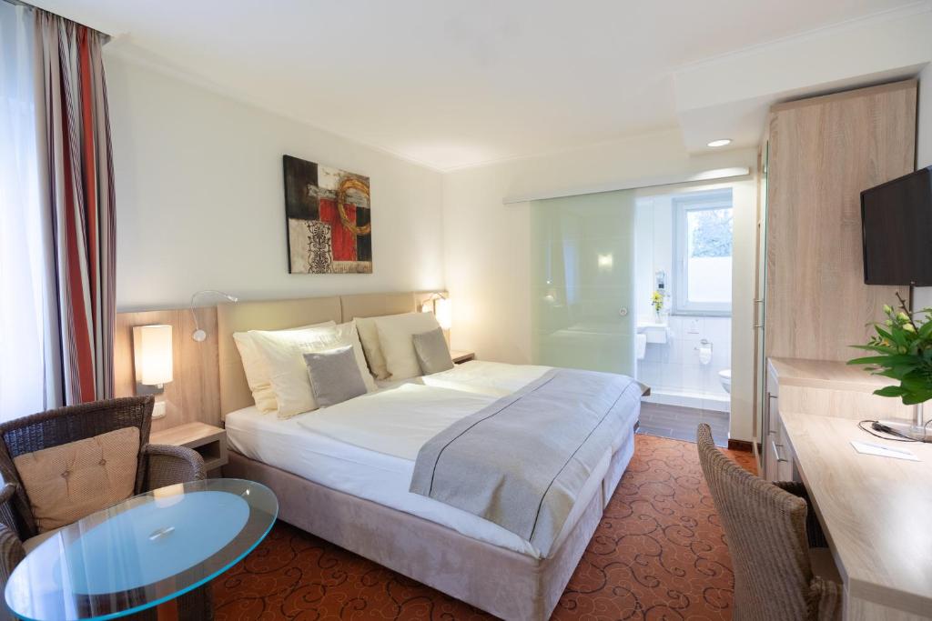 不莱梅Novum Hotel Garden Bremen - Apartments的酒店客房设有一张床铺、一张桌子和一间浴室。