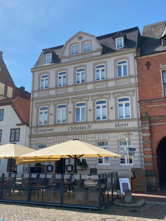 格吕克斯塔特Hotel & Restaurant Christian IV的前面有桌子和伞的建筑