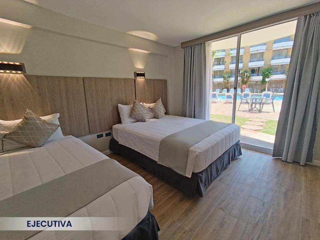 波拉马尔Hotel Margarita Dynasty的酒店客房设有两张床和大窗户。