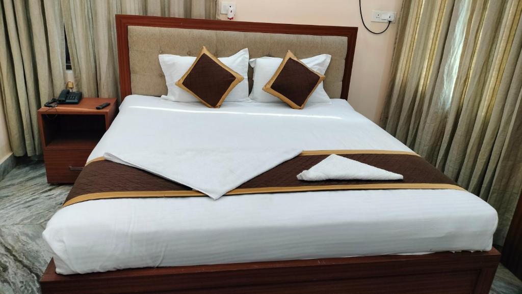 瓦拉纳西Hotel Kashyaam Inn的卧室配有带枕头的大型白色床