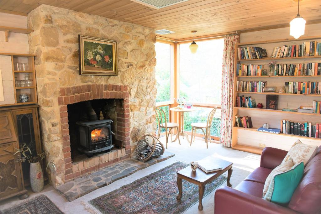 克拉佛斯Adelaide Hills Camellia Cottage Wifi的客厅设有石制壁炉和沙发。