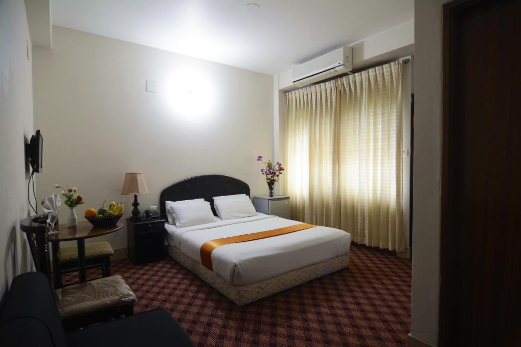 达卡随心假日酒店 的一间卧室配有一张床、一张书桌和一个窗户。