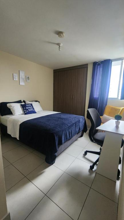 Ciudad RadialQuédate con sulay habitación a 5mint del aeropuerto的一间卧室配有一张床、一张桌子和一把椅子