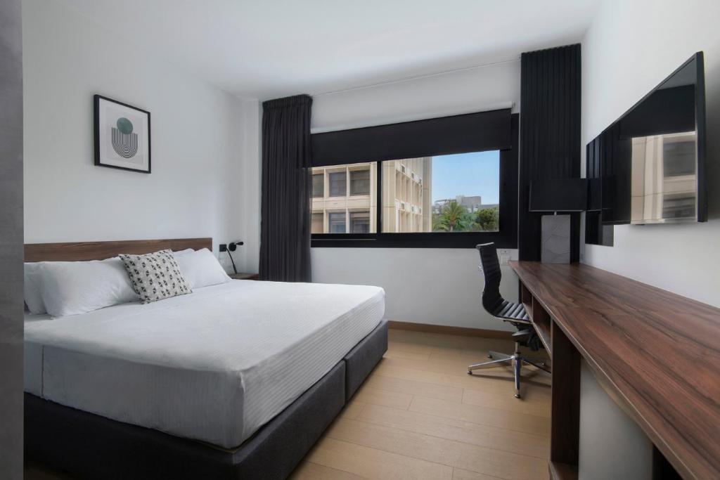 尼科西亚Urban Habitat Executive Suites的一间卧室配有一张床、一张书桌和一个窗户。