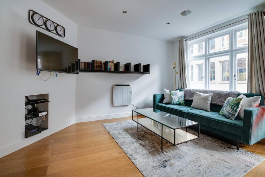 伦敦Lovely Charing Cross Apartment的客厅配有绿色沙发和电视