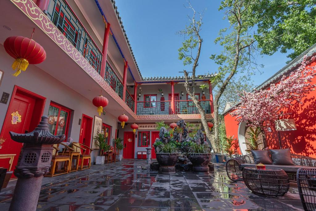 北京荣府老宅酒店(北京南锣鼓巷店)的一座带红色墙壁和椅子的建筑的庭院